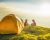 Kids in colorful outdoor clothing sitting beside a bright yellow dome tent camped in an idyllic mountain top meadow illuminated by the warm light of a summer sunset. ProPhoto RGB profile for maximum color fidelity and gamut.